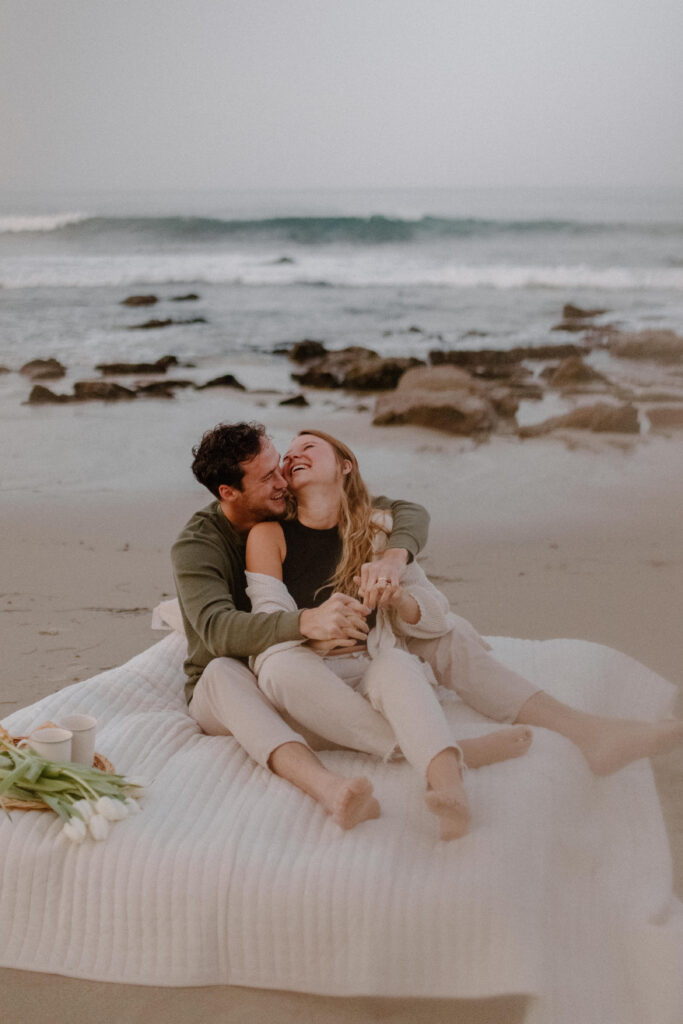 an engaged couple enjoying their engagement photo session on the beach after learning wedding planning tips 