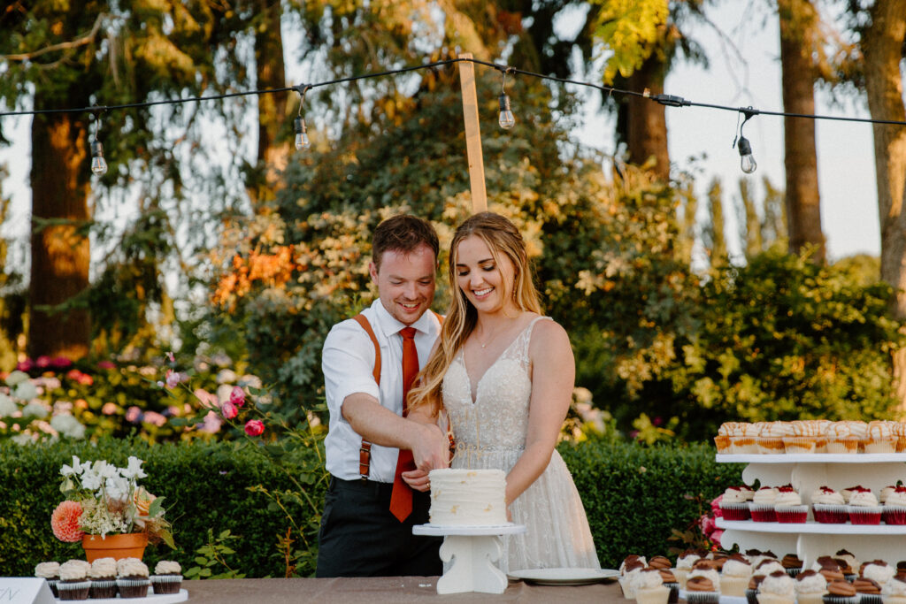 A bride and groom cutting the cake at their garden venue after learning wedding planning tips 