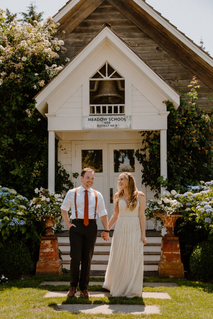 A bride and groom smiling at each other on their wedding day in their schoolhouse garden venue after learning wedding planning tips