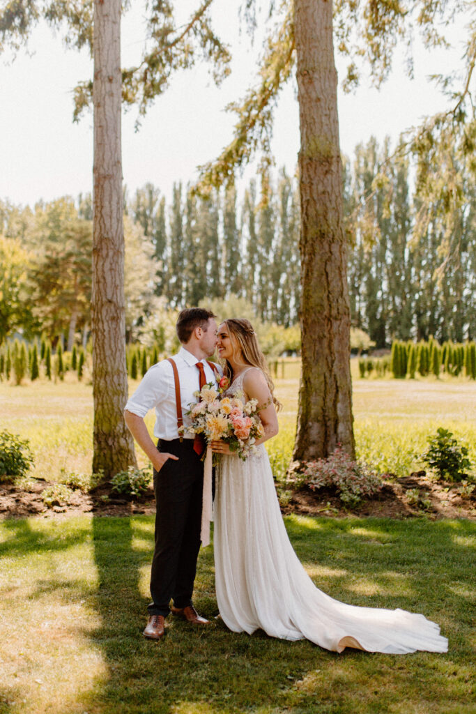 A bride and groom looking lovingly at each other holding flowers in their garden venue after learning wedding planning tips