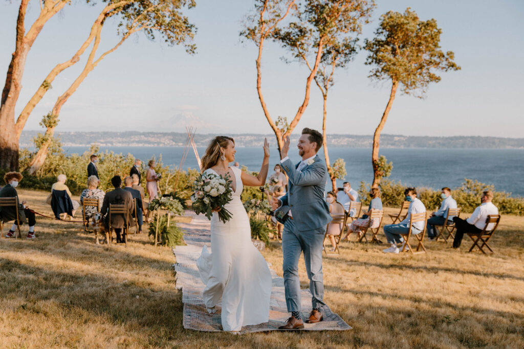 A bride and groom giving each other a high five after getting married at a mountain view venue on Vashon Island in Washington after learning wedding planning tips 