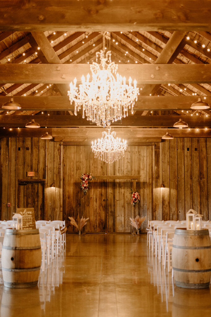Interior barn wedding ceremony set up with white chairs, a large chandelier and an alter with flowers decorating it. 
questions for wedding vendors