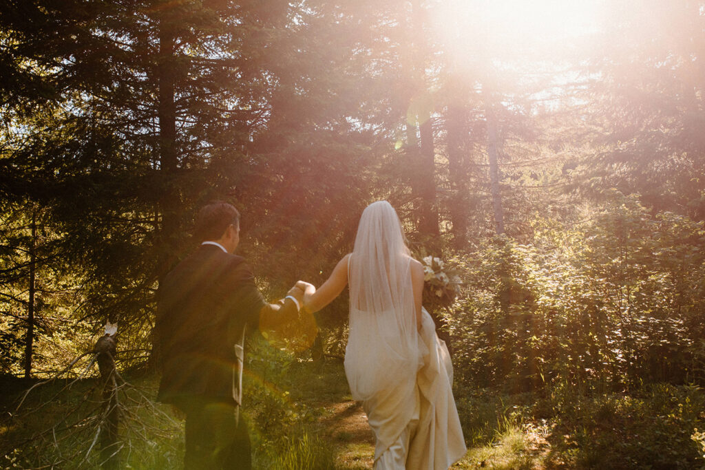 A bride and groom walking towards the forrest after their elopement to have a moment to take it in and enjoy the scenery after learning wedding planning tips