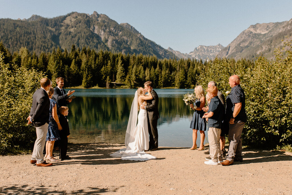A bride and groom share their first kiss at their mountain view elopement after learning wedding planning tips