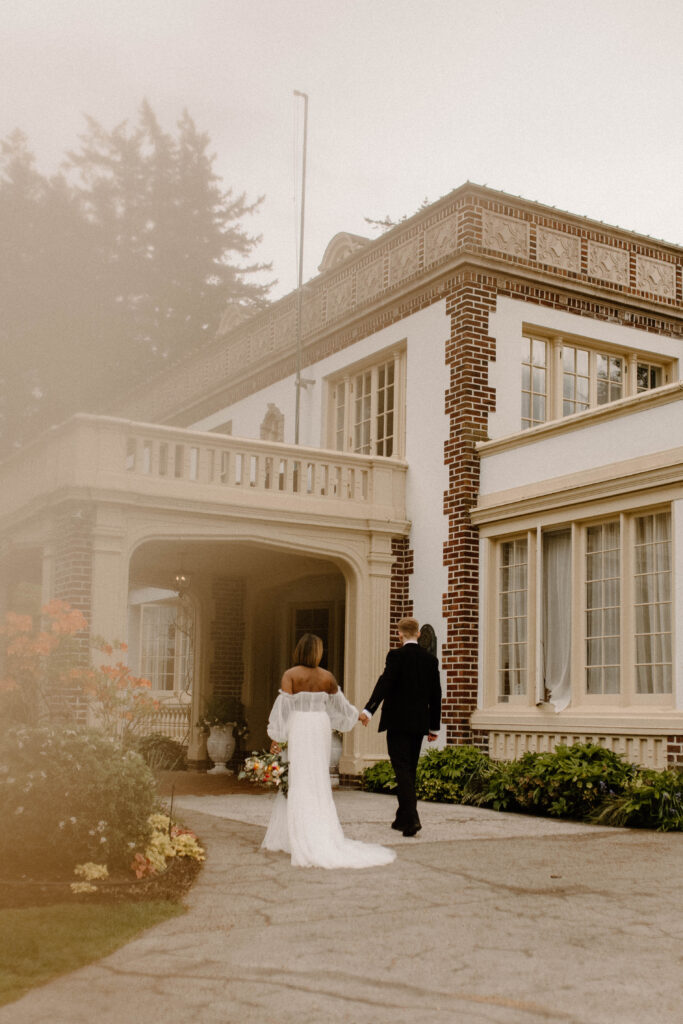 A bride and groom walking towards their manor venue in bellingham washington after learning wedding planning tips 