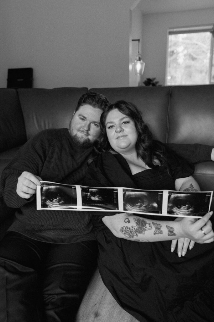 Couple holding a baby ultrasound during their in home pregnancy announcement photoshoot.