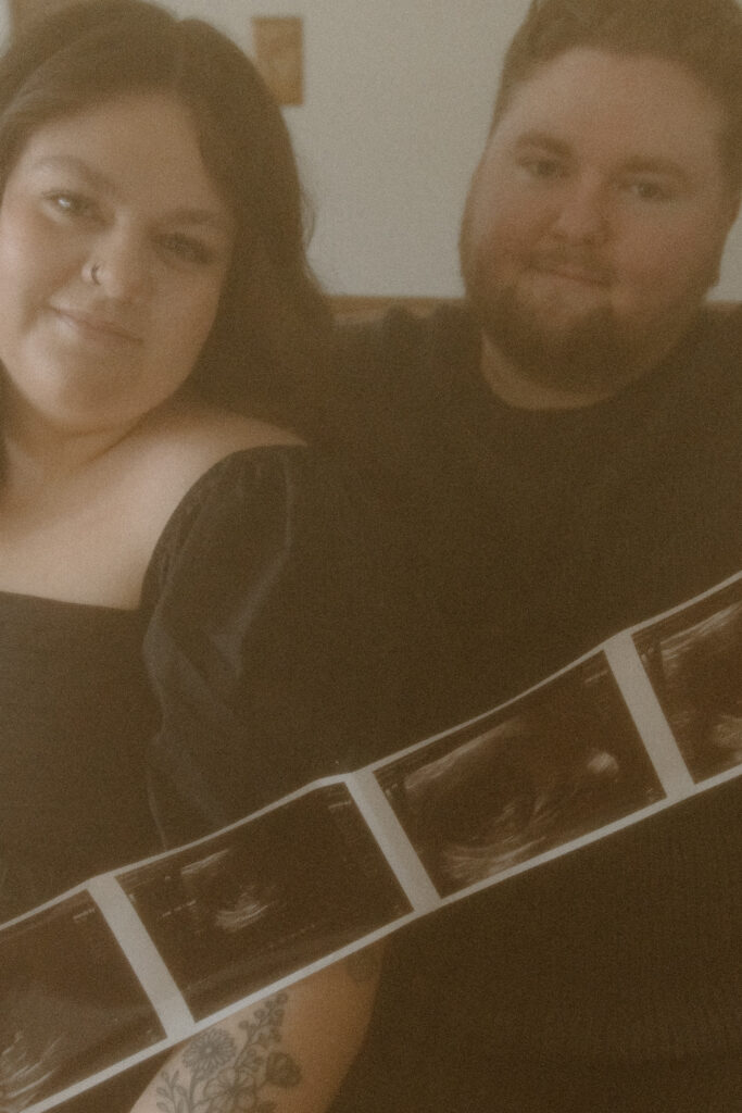 Couple holding a baby ultrasound during their in home pregnancy announcement photoshoot.