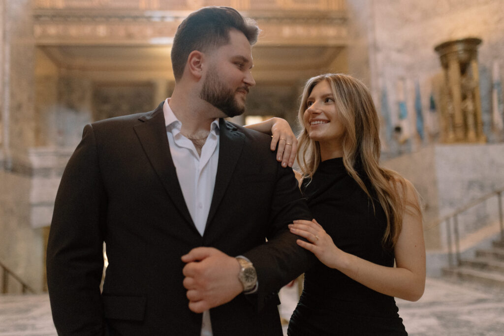 Man and women smiling at each other while modeling for classic engagement photos at the Washington State Capitol Building.