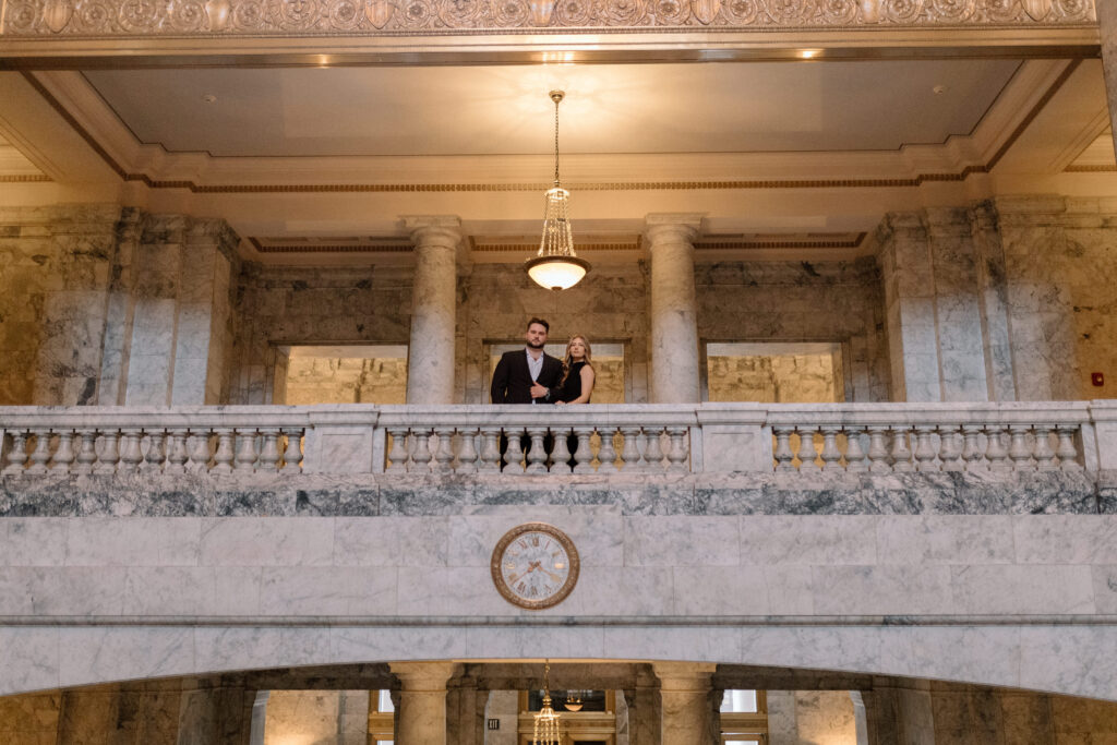 Couple inside a grand building posing for engagement photos.