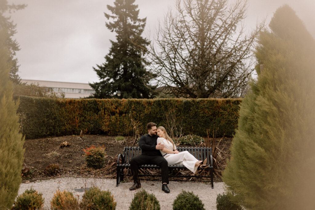 A couple sitting on a garden bench during their engagement photoshoot.