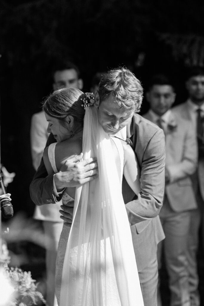 black and white photo of bride and groom hugging during wedding ceremony