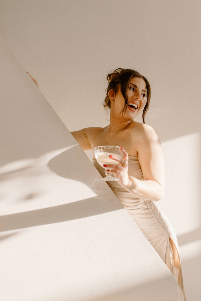 portrait of a woman cheering with a glass of champagne smiling to the side.