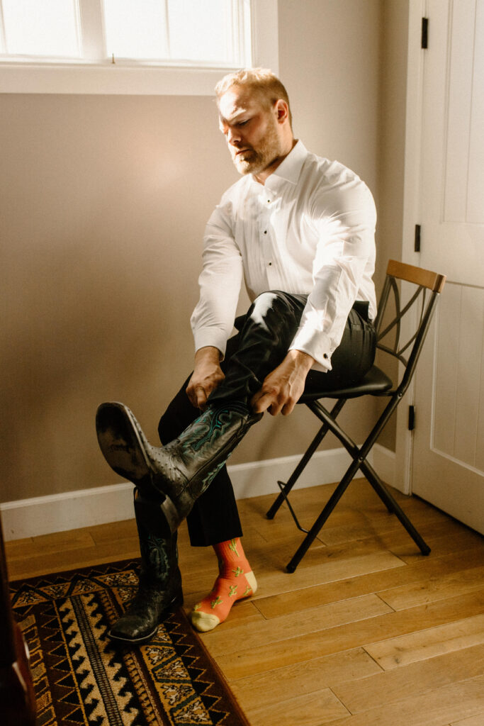 country Colorado wedding groom getting ready putting on cowboy boots