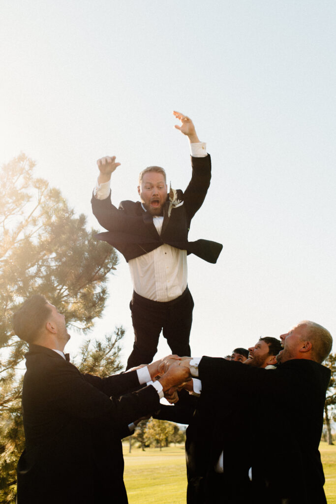 fun groomsman photo groom thrown in the air