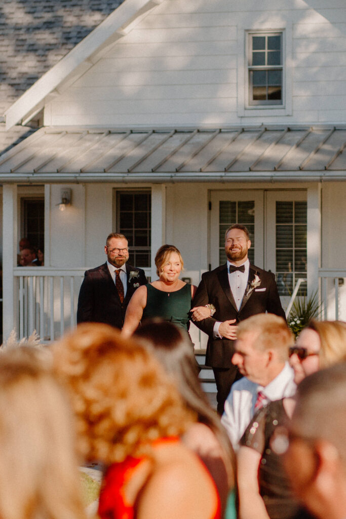 groom walking down the aisle with parents