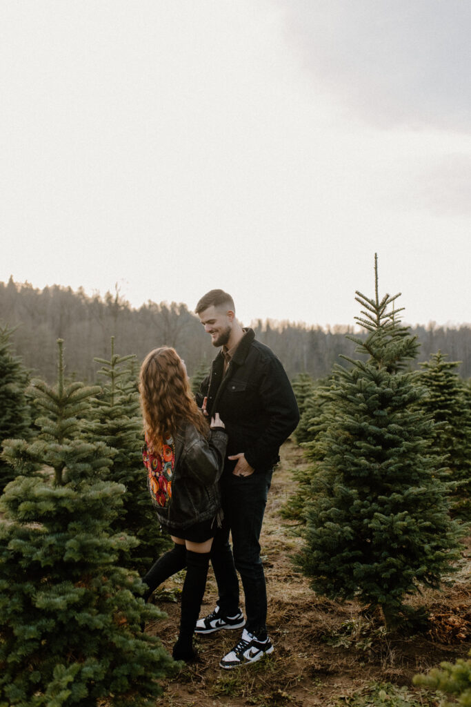 couples posing for holiday tree farm photoshoot