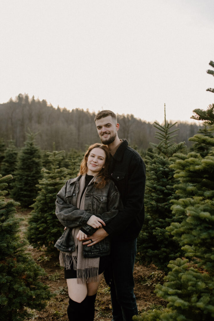 couples posing for holiday tree farm photoshoot