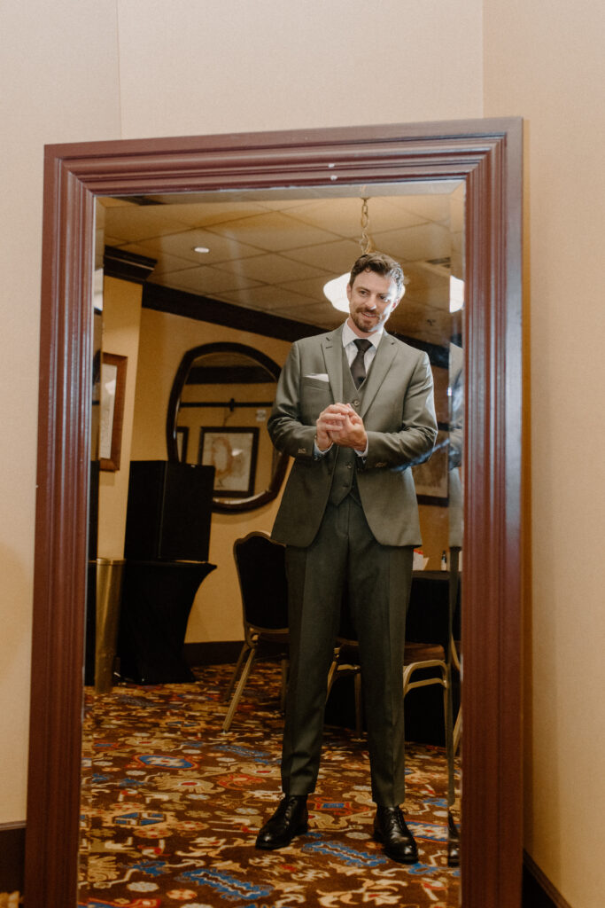groom getting ready for wedding day in front of mirror